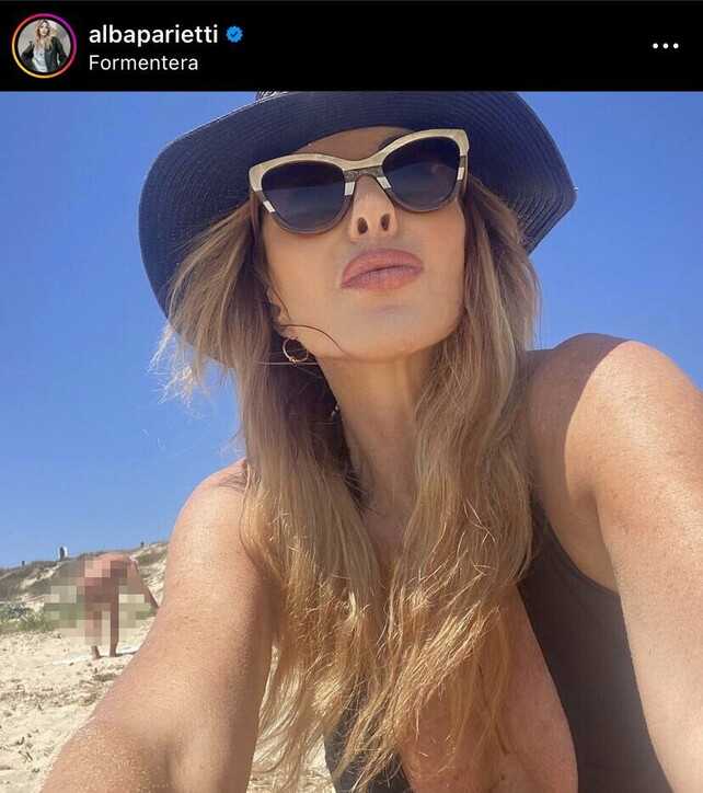 Alba Parietti posta un selfie in costume a Formentera ma un uomo nudo dietro di lei le ruba la scena